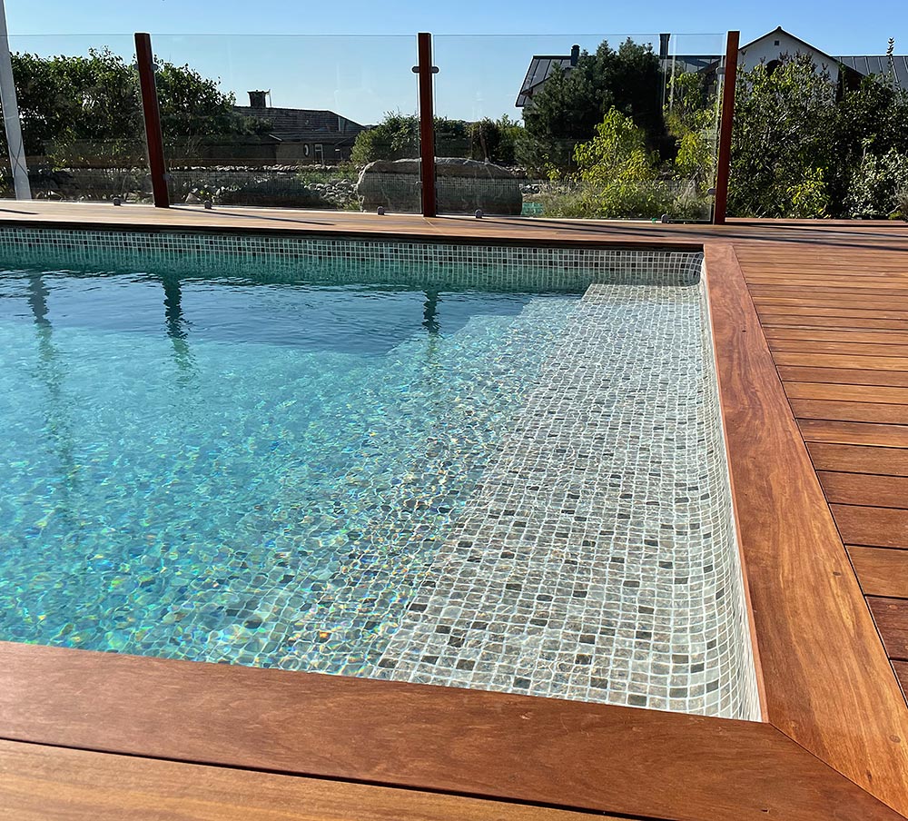 Vackert omgivande trädäck med gaveltrappa och mosaikliner - poolinspiration från kund